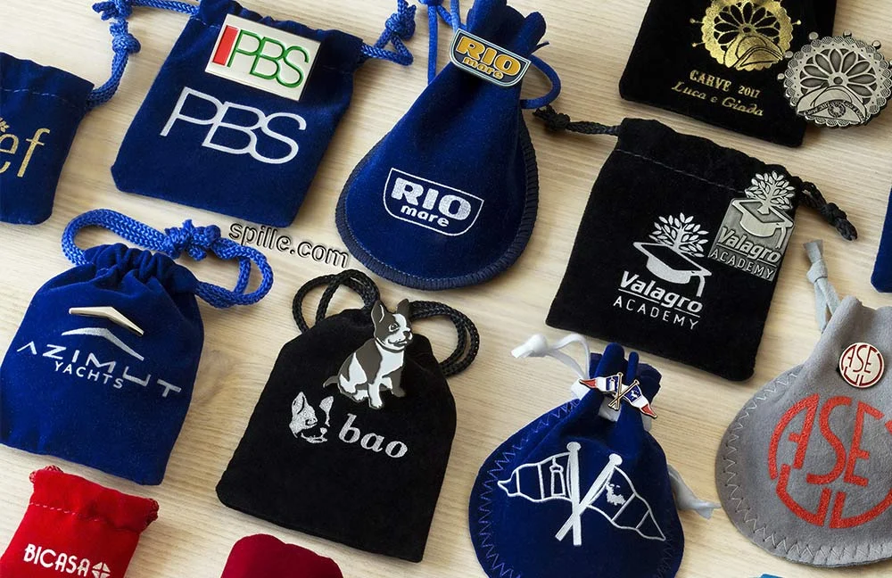 Esempi di sacchetti personalizzati in velluto per valorizzare ancora di più le spille con brillantini, varie forme, dimensioni e colori, possibilità di stampare la grafica o motto del cliente direttamente sul sacchettino