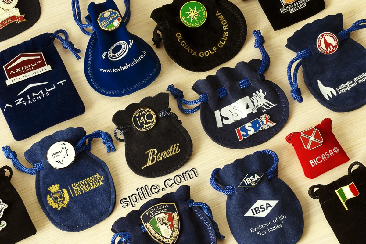 Assortimento di spille de luxe con sacchettino personalizzato in velluto in varie forme, dimensioni e colori con il logo stampato sopra